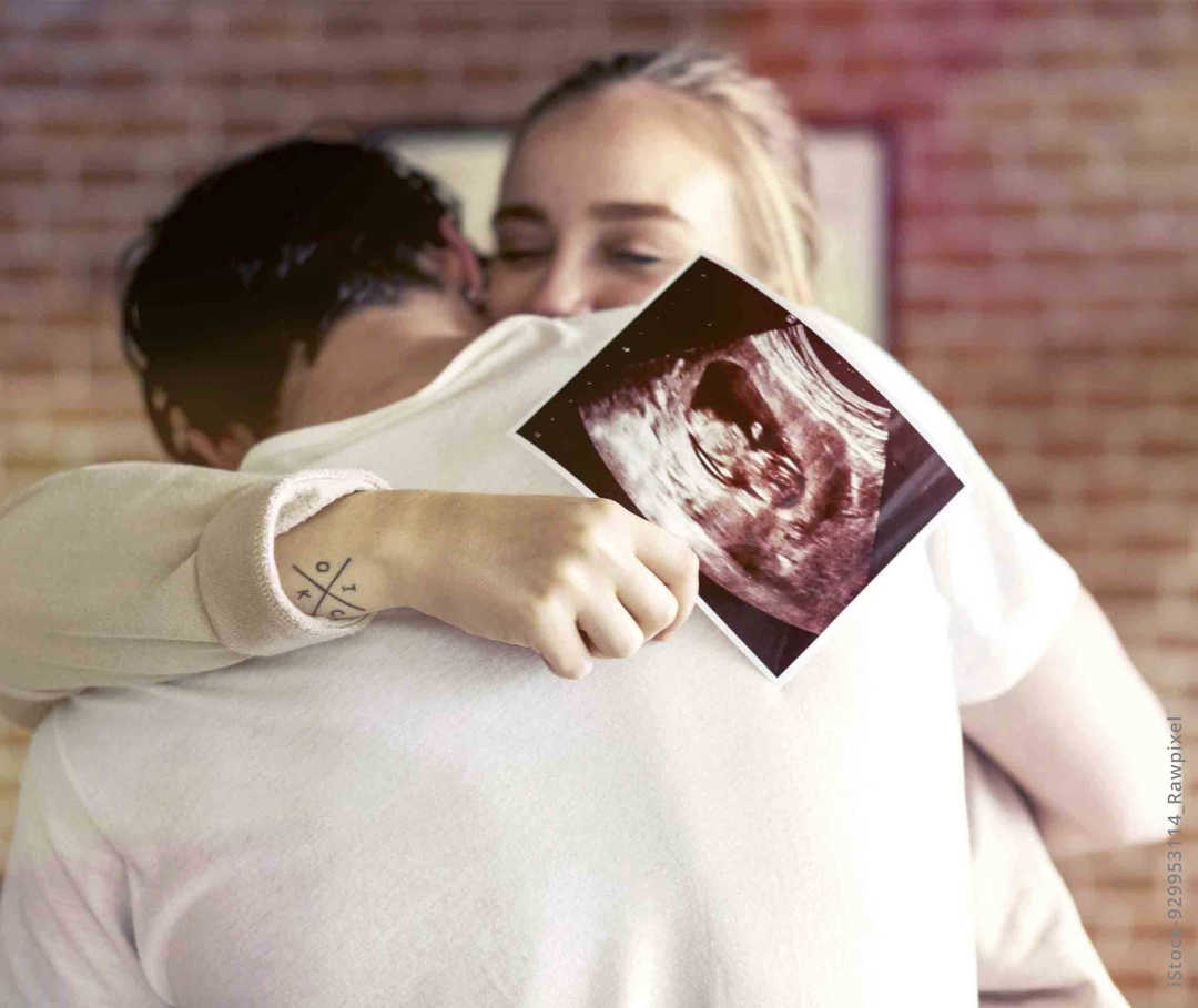 MS und ich: Eine glückliche Frau umarmt ihren Partner. In der Hand hält sie ein Ultraschallbild MS und ich: Eine glückliche Frau umarmt ihren Partner. In der Hand hält sie ein Ultraschallbild