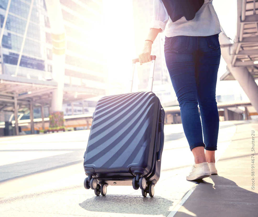 MS und ich: Eine Frau zeiht bei strahlendem Sonnenschein einen vierrädigen Koffer hinter sich her MS und ich: Eine Frau zeiht bei strahlendem Sonnenschein einen vierrädigen Koffer hinter sich her