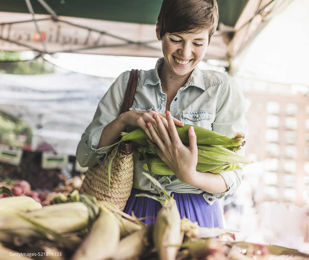 MS und Ernährung Eine Frau auf dem Markt mit Maiskolben in den Händen